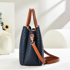 Detail of navy blue woven tote bag with brown straps and golden metal hardware