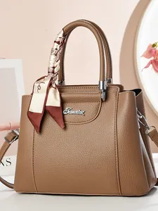 Elegant brown pebbled leather handbag with decorative silk scarf and metal logo