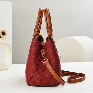 Detail of woven burgundy texture and gold hardware on the elegant shoulder bag
