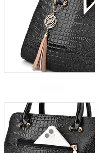 Detail of black crocodile texture handbag featuring golden tassel and back zipper pocket