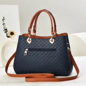 Close-up of woven texture shoulder bag with blue body, tan handles and gold hardware