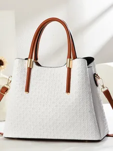White woven textured tote bag with brown leather handles and gold metal hardware accents