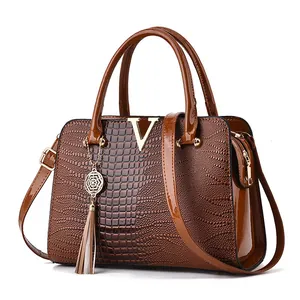 Brown crocodile embossed tote bag with gold V hardware and elegant tassel detail