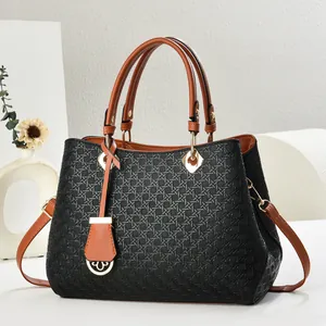 Detail of woven texture black shoulder bag with brown handles and gold hardware accents