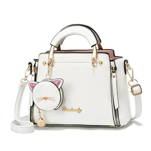 Close-up of white leather handbag with golden logo and cute cat-shaped coin purse charm