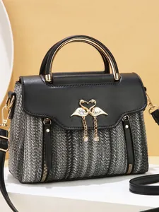 Elegant grey woven crossbody bag with golden swan clasp and pearls on warm background