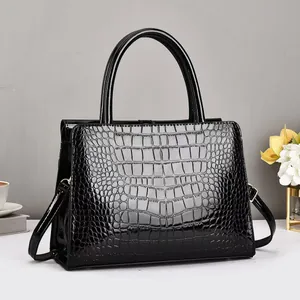 Detail of black faux crocodile patent leather handbag with silver metallic clips