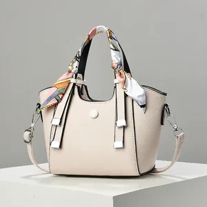 Detailansicht der cremefarbenen Ledertasche mit Lychee-Struktur und floralem Seidenschal