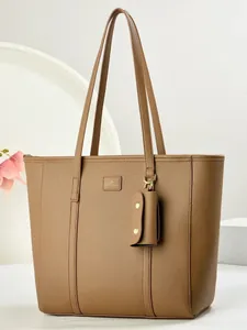 Braune Shopper-Tasche aus genarbtem Leder mit Schultergurt und Anhänger auf weißem Sockel