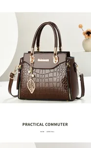 Detailed view of brown handbag with crocodile embossed texture and pearl leaf charm