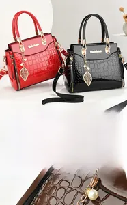 Detail of embossed crocodile pattern handbag with golden pearl leaf pendant and hardware