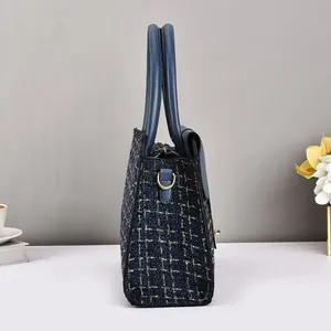 Side view of elegant tweed handbag with navy leather trim and gold metal D-ring details