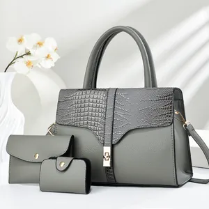 Three-piece grey tote set with crocodile texture and gold lock in a minimalist setting