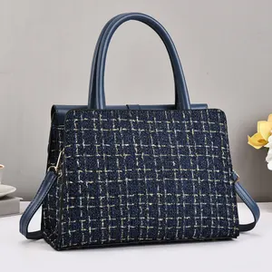 Detail of tweed crossbody bag with blue leather handle and golden metallic clasp