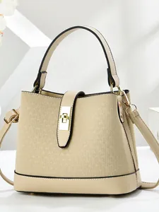 Cream knit bucket bag with leather trim and gold metal lock on geometric white background