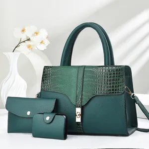 Detail of dark green tote bag set with crocodile texture and gold hardware accents