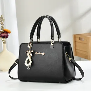 Close-up of black crossbody bag with cross-grain texture and elegant pearl bow pendant