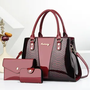 Close-up of burgundy three-piece bag set with snakeskin texture and polished finish