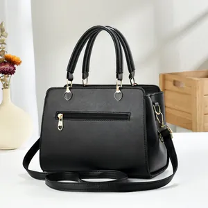 Detail of black Saffiano leather tote with golden heart charm and functional back zipper