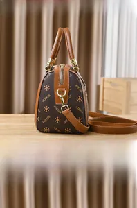 Detailed side view of brown monogram Boston bag with gold hardware and leather handles