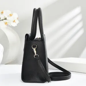 Detail of black pebbled leather tote with gold hardware and side profile profile view
