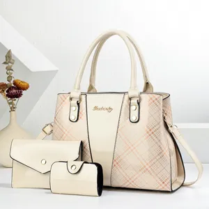 Detailed view of glossy cream faux leather three-piece tote set with logo and gold hardware