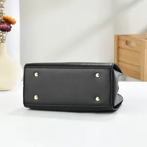 Detail of black Saffiano leather bag base with four protective gold metal feet studs