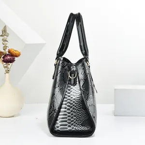 Detail of snake pattern texture and golden metal hardware on a black handbag