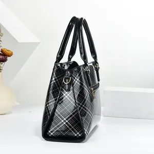Detail view of large checkered patent leather tote bag with elegant gold metal hardware