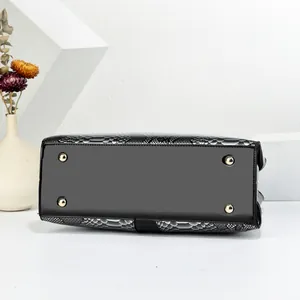 Detail of black leather bag base with golden protective studs and snake pattern trim