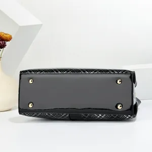 Detail of glossy patent leather bag bottom with four protective gold metal feet studs