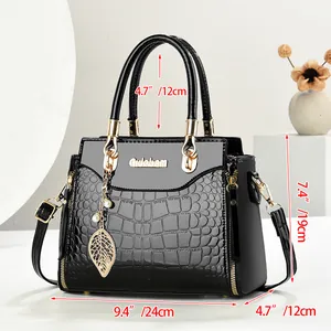 Close-up of black crocodile pattern leather handbag with gold leaf charm and pearl detail