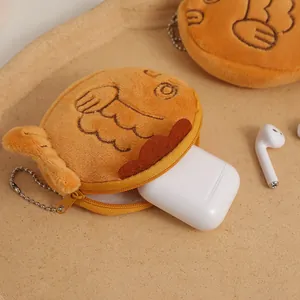 Detail of taiyaki plush pouch holding wireless earbuds with silver metal chain