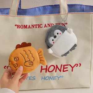 Close-up of cute cartoon penguin and taiyaki plush coin purses hanging on a bag