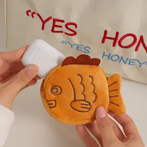 Detail of cute orange plush fish pouch holding a wireless earphone charging case
