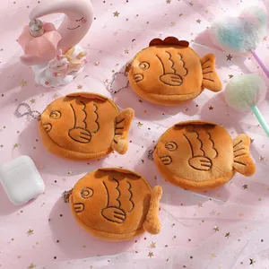 Detail showing four plush fish coin purses with zipper and chain on pink mesh background