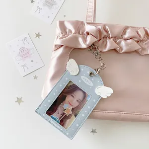 Detail of light blue PU card holder with angel wings hanging on a pink satin bag