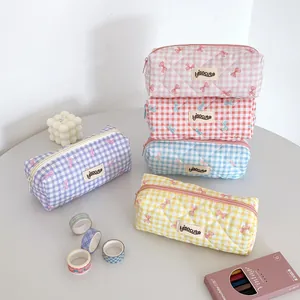 Macro shot of assorted cream grid pencil cases with cute bows and premium fabric textures