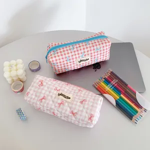 Detail showing two quilted cream plaid pencil cases with elegant ribbon bow patterns