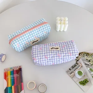 Close-up of quilted cream checkered pencil bags with pink bows and zipper closure