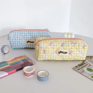 Detailed view of cream checkered stationery pouches with soft bow embroidery and brand label