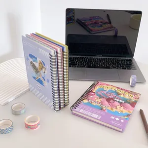 Detail view of dessert themed spiral notebooks on desk with stationery and laptop
