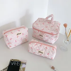 Detailed view of pink plaid quilted toiletry bag set with cute red bow patterns