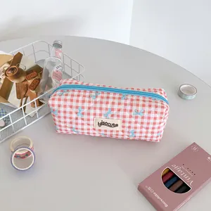 Detail of pink plaid pencil case featuring blue bow patterns and hisocute label