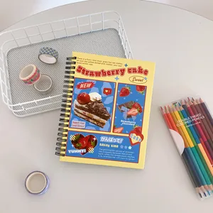 Close-up of A5 spiral notebook with strawberry cake design and yellow cover art