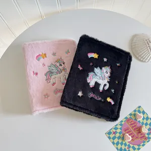 Detail of plush A5 binder cover featuring unicorn embroidery and colorful accents