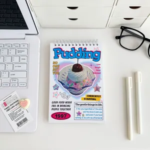 Top coil notebook with retro pudding illustration on a desk with office supplies