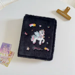 Close-up of black plush binder cover featuring embroidered unicorn and stars design