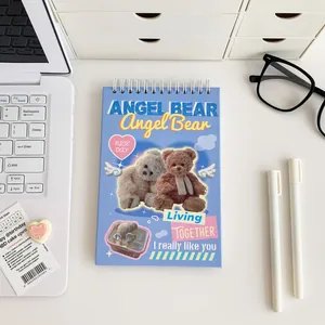 Detail of light blue spiral weekly planner with Angel Bear motif on a desk setup