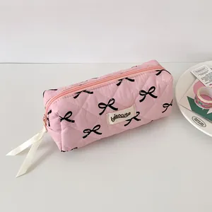 Dettaglio dell'astuccio trapuntato rosa con fiocchi neri e tirante in nastro di seta